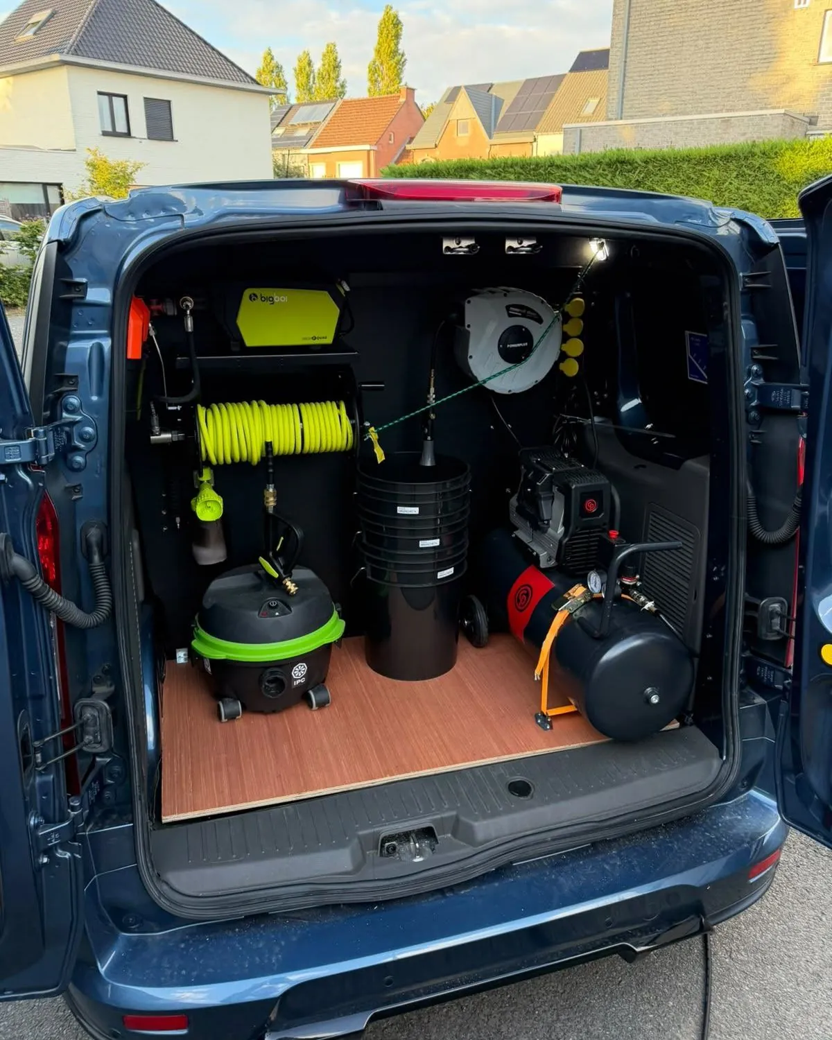De bus van TB Car Cleaning met open achterdeuren: slanghaspel, stofzuiger, emmers en compressor vast ingebouwd