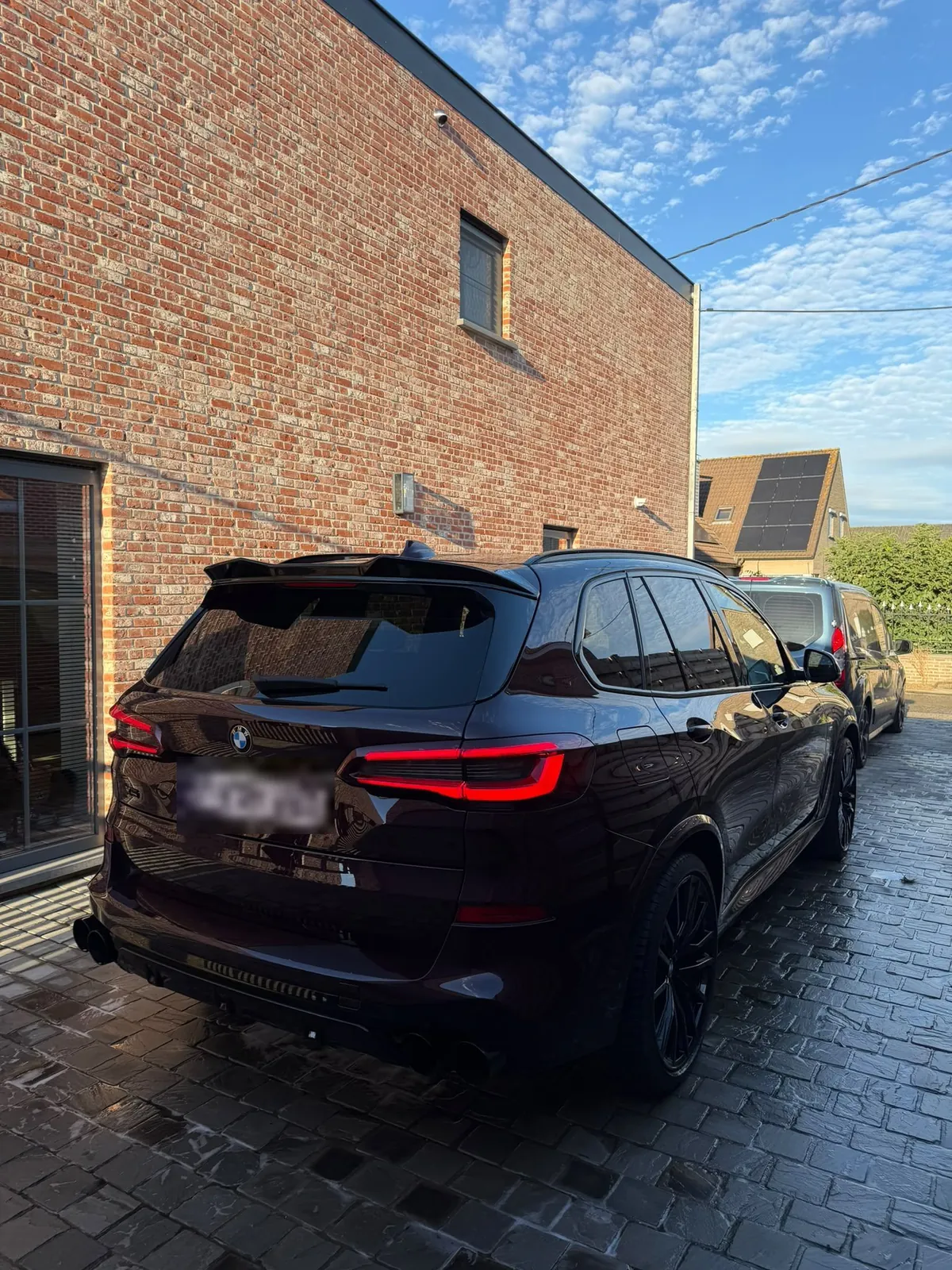 Achterkant van de gewassen BMW X5, met de bus van TB Car Cleaning erachter