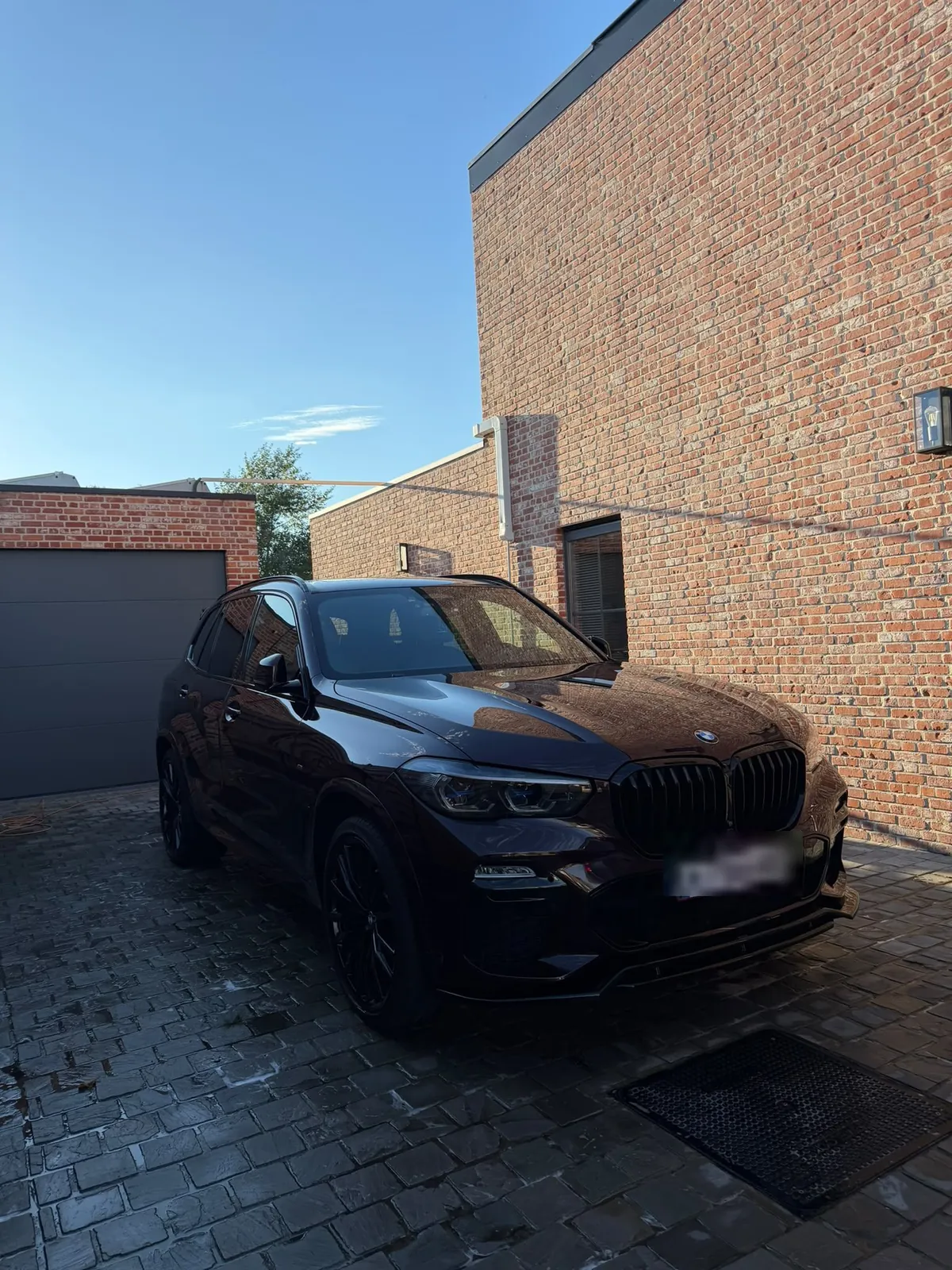 Dezelfde BMW X5 gewassen en gedroogd, vooraanzicht op de oprit